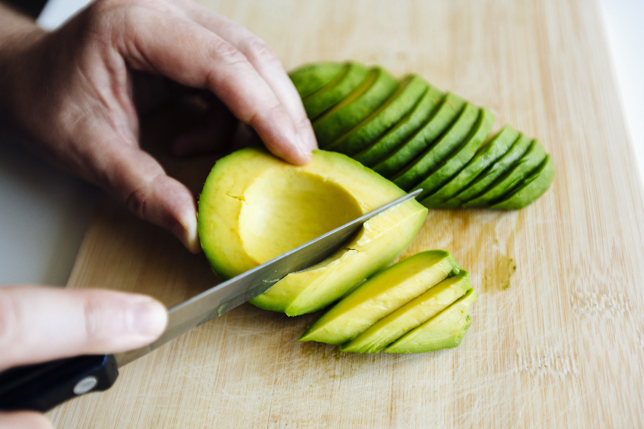 a hand slicing an avocado