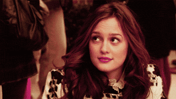 A close up of Blair Waldorf as she smiles and rests her chin in her hand