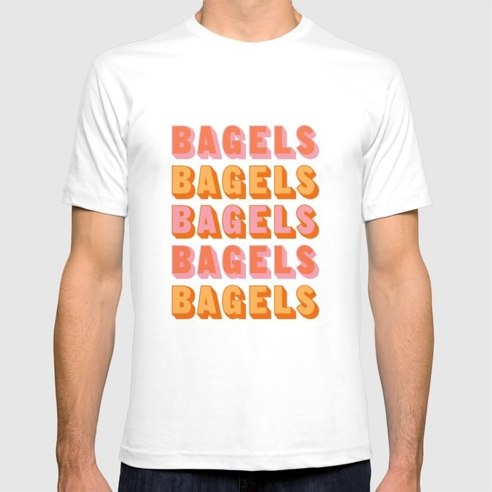 a model wearing the white shirt which says &quot;bagels&quot; five times in orange and pink text