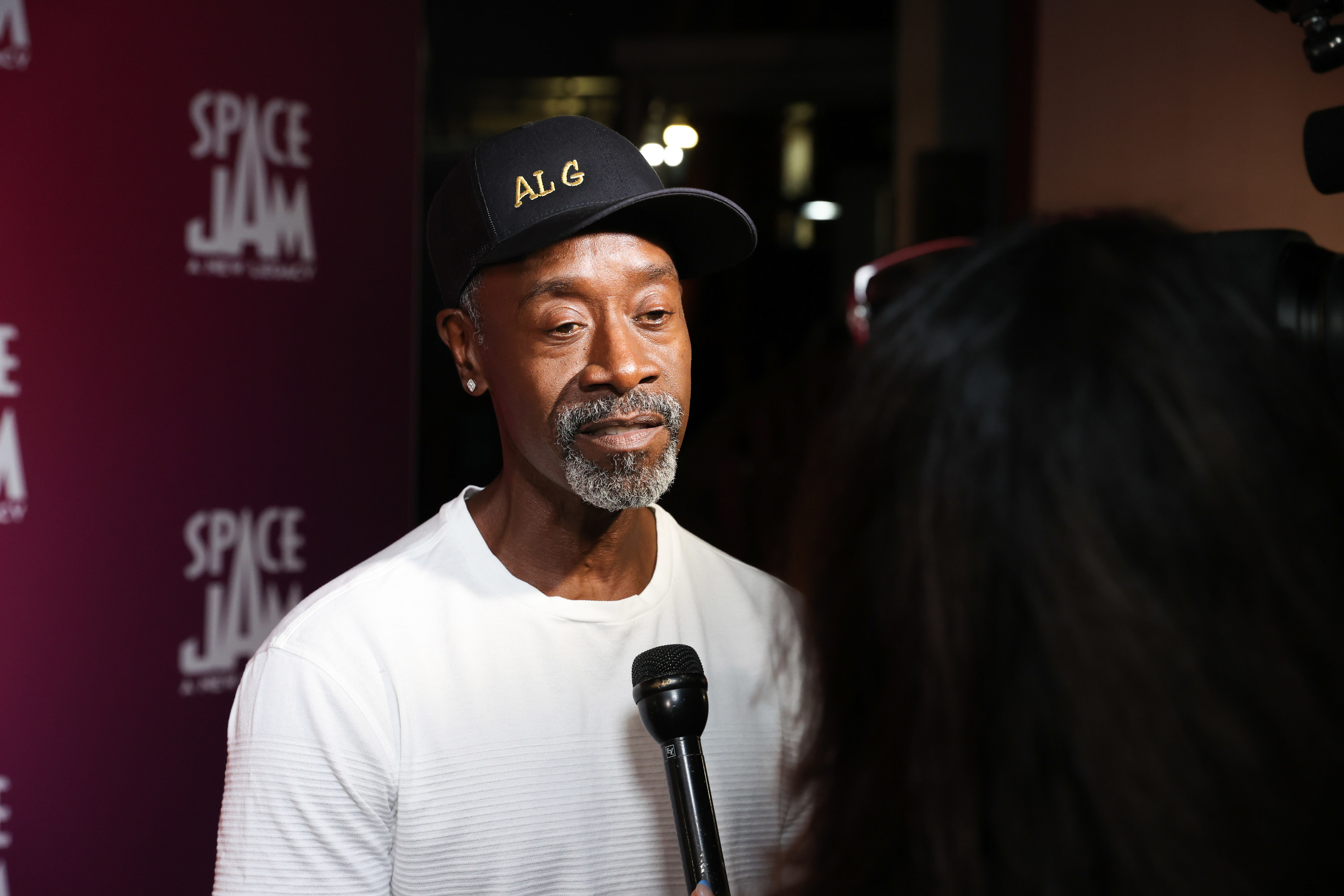 Don Cheadle speaks into a microphone during a red carpet interview