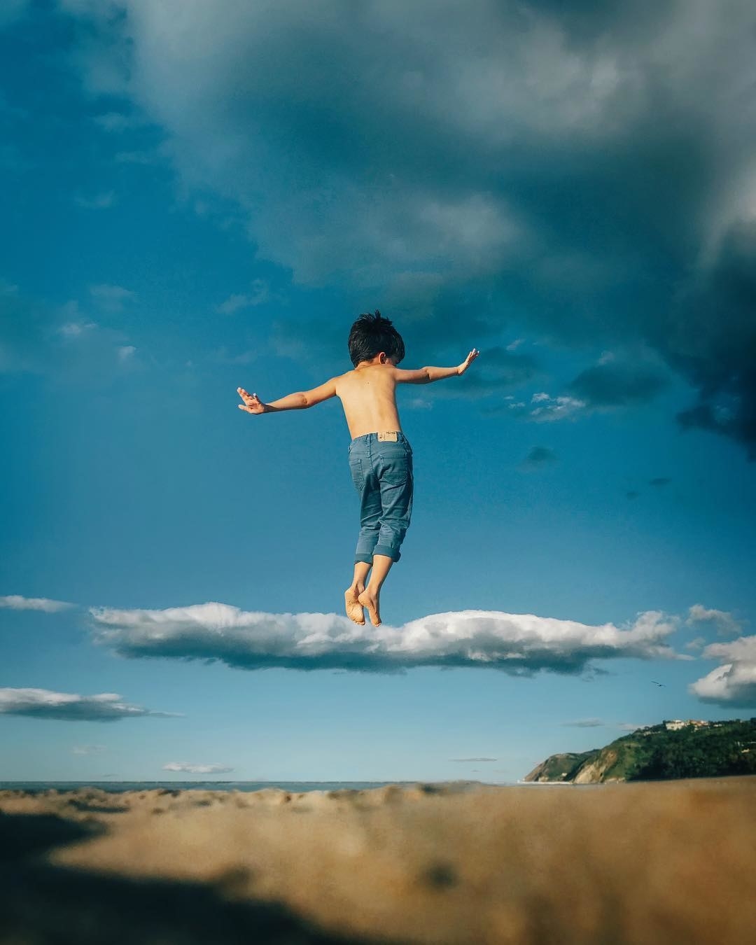 A young boy in mid-air seems to balance their tip-toes on a cloud