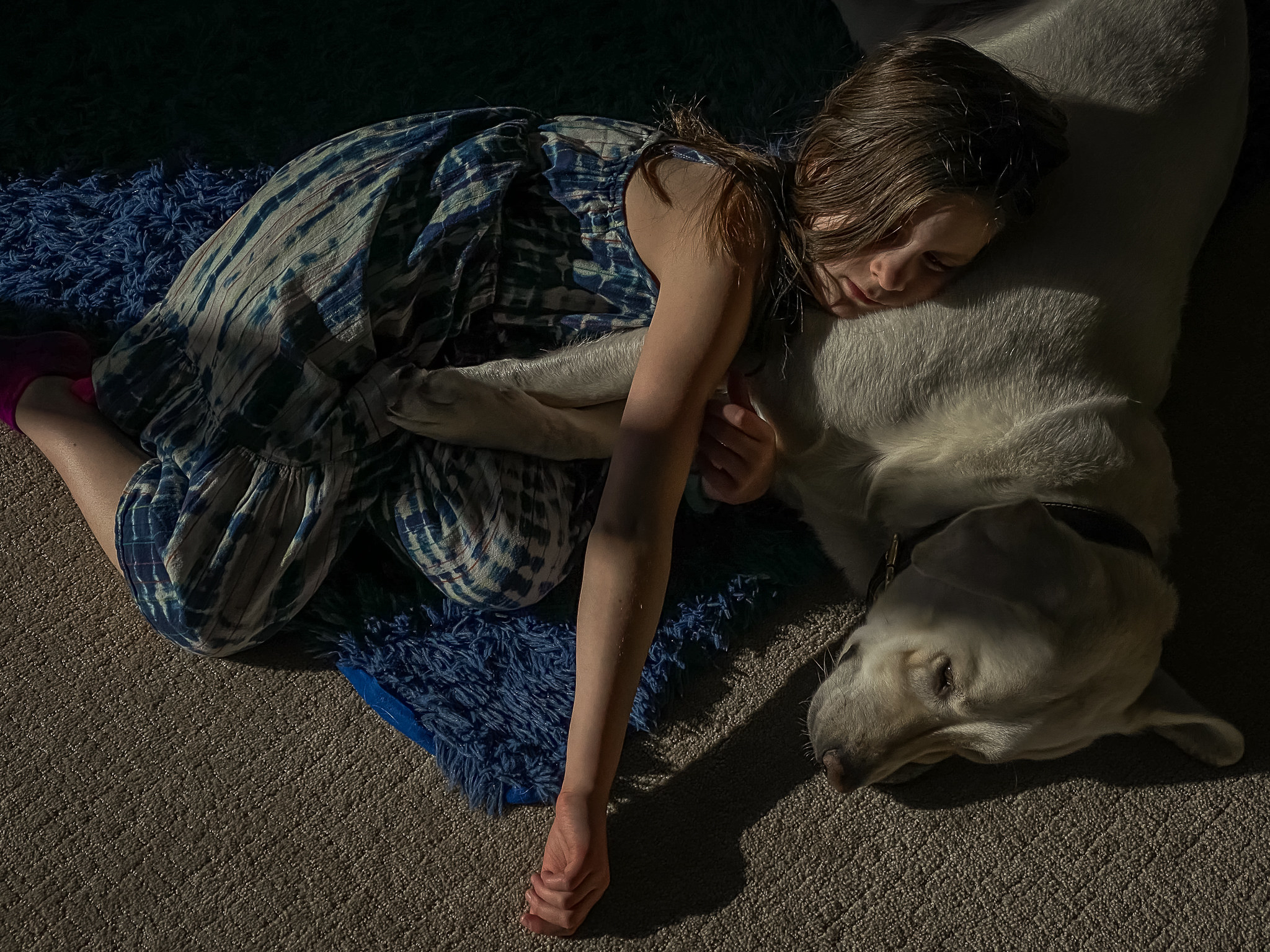 A girl sleeping on the floor with a dog at night