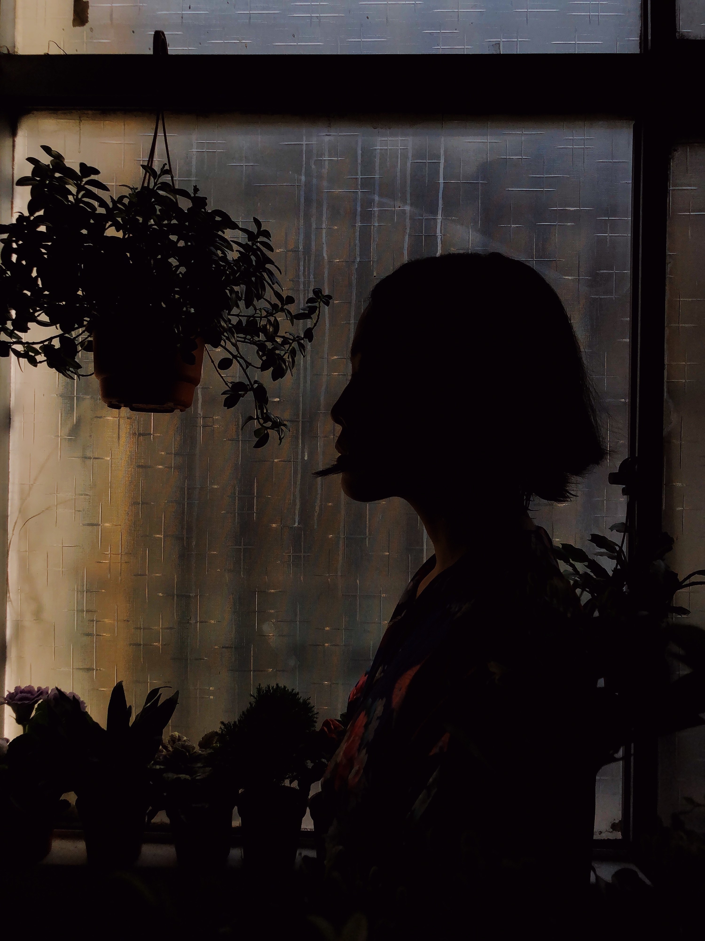 A woman in silhouette in front of a window in the dark