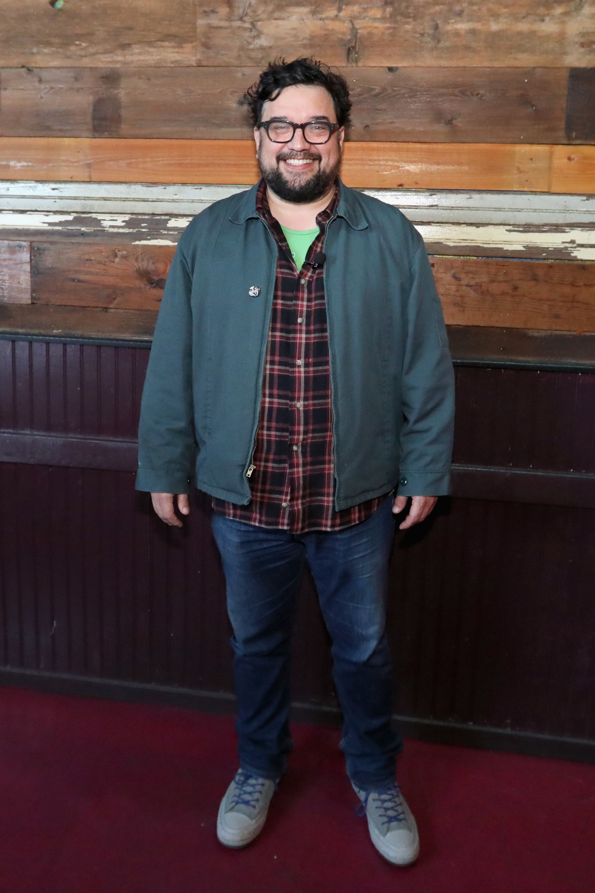 Sanz poses for a picture while wearing jeans, a jacket, and a button-down shirt