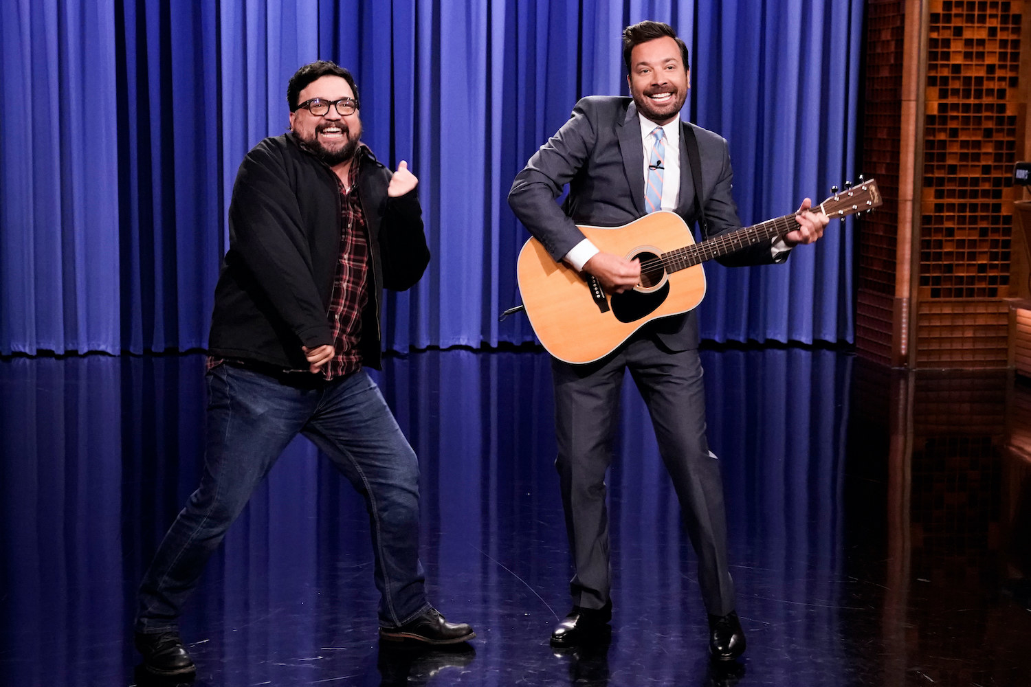 Horatio Sanz and Jimmy Fallon dance together on stage in front of a curtain
