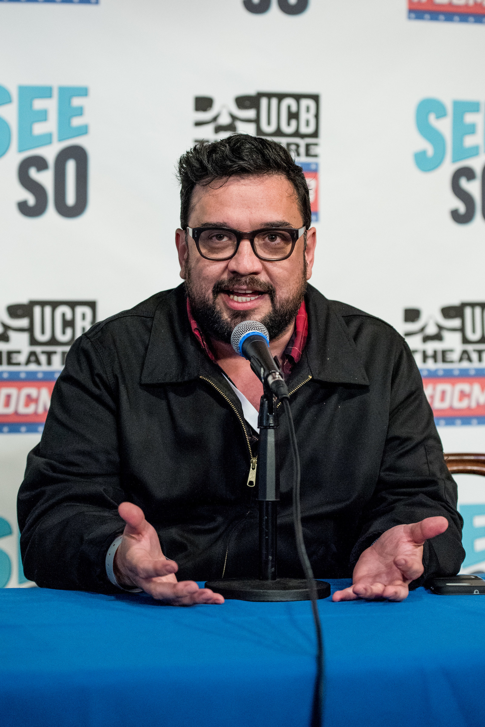 Sanz talks into a microphone with his hands resting on a table at a panel