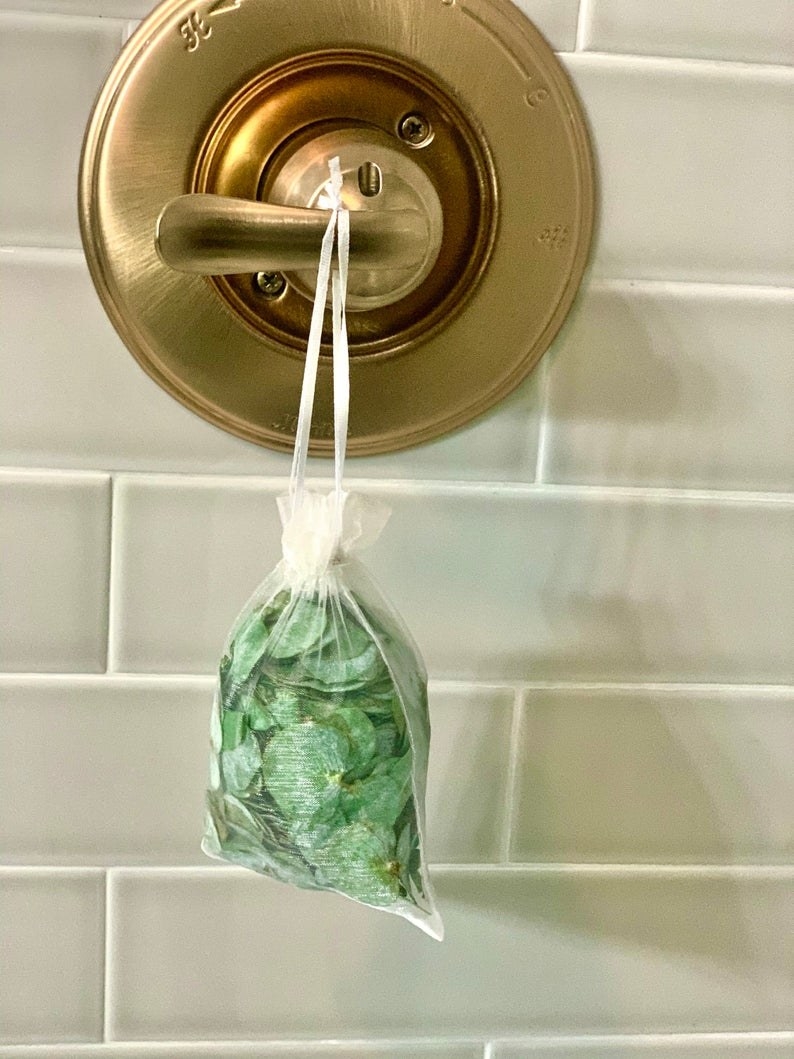 a eucalyptus shower pouch hanging from a bathtub's handle valve