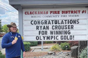 Ryan Crouser pictured with his gold medal at a fire station that has a marquee sign congratulating him