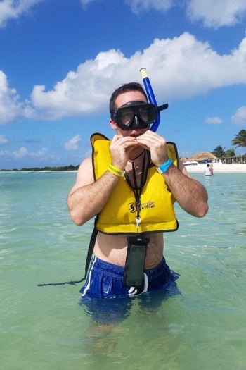 reviewer with the black waterproof case around neck while in the water