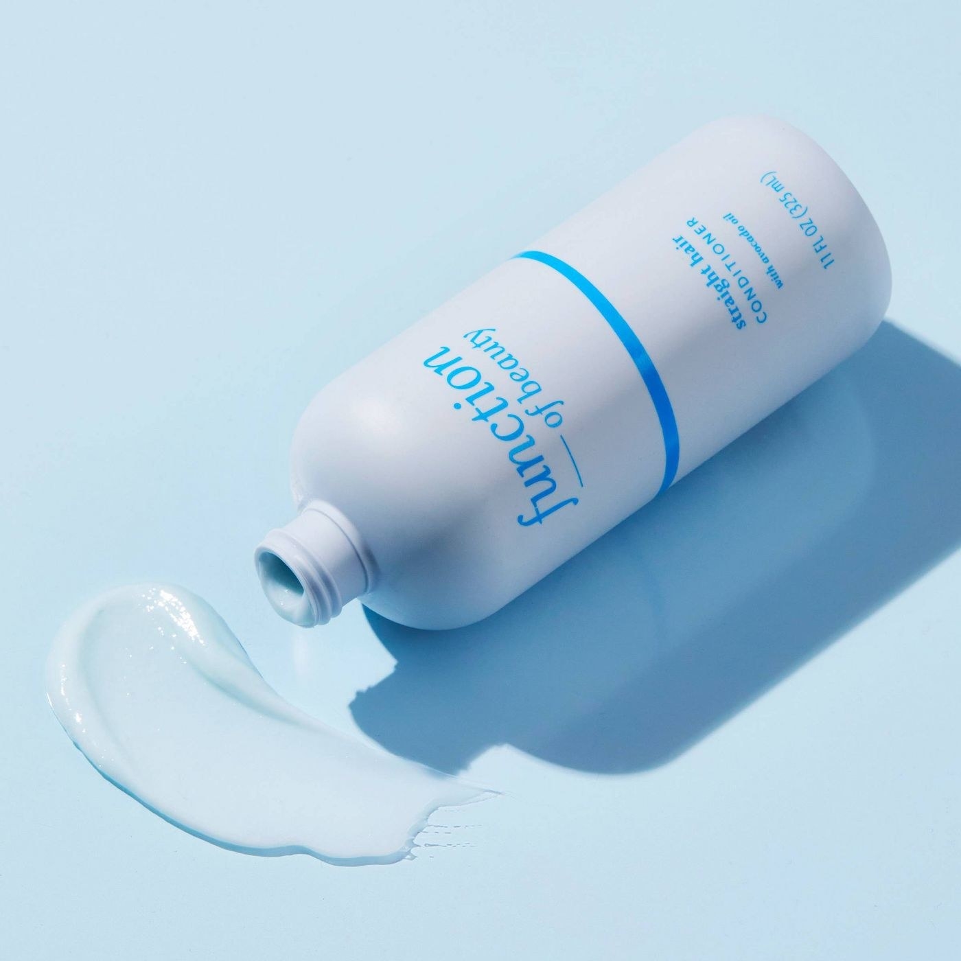 A blue bottle of hair conditioner on a blue backdrop with a swatch