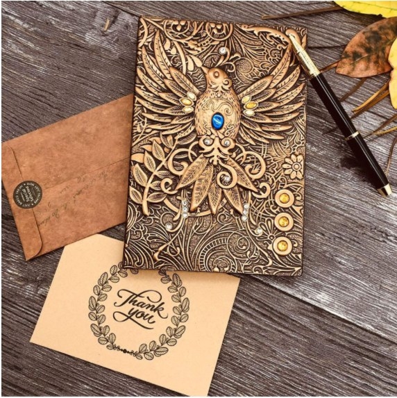 Foto de cuaderno de piel en color bronce rojizo con relieve de un pajaro