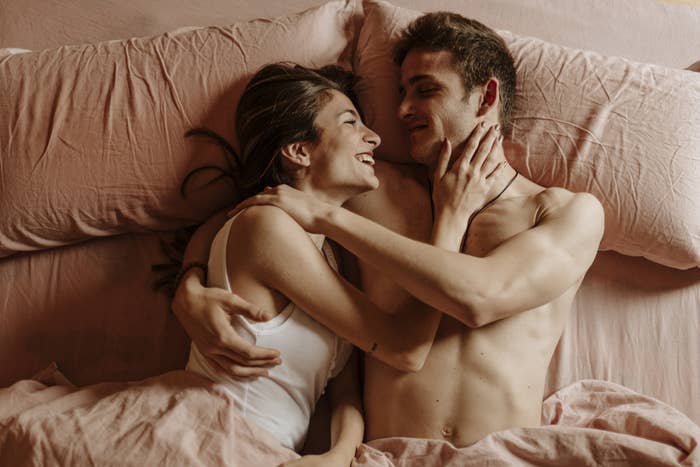 A man and woman in bed smiling at each other