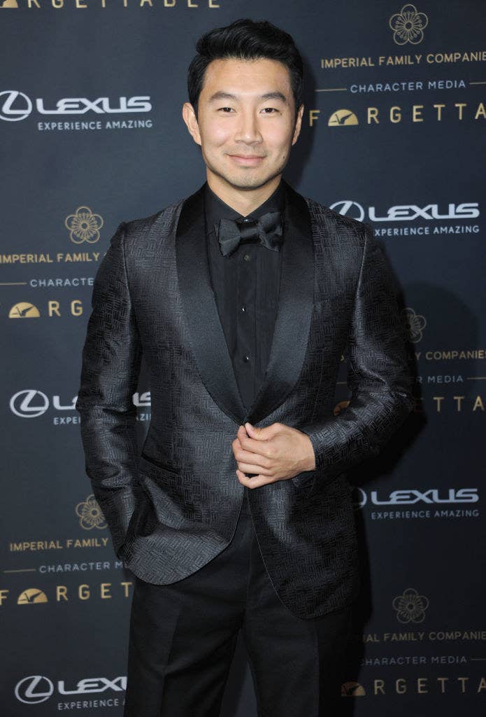 Simu Liu posing on a red carpet in a textured suit