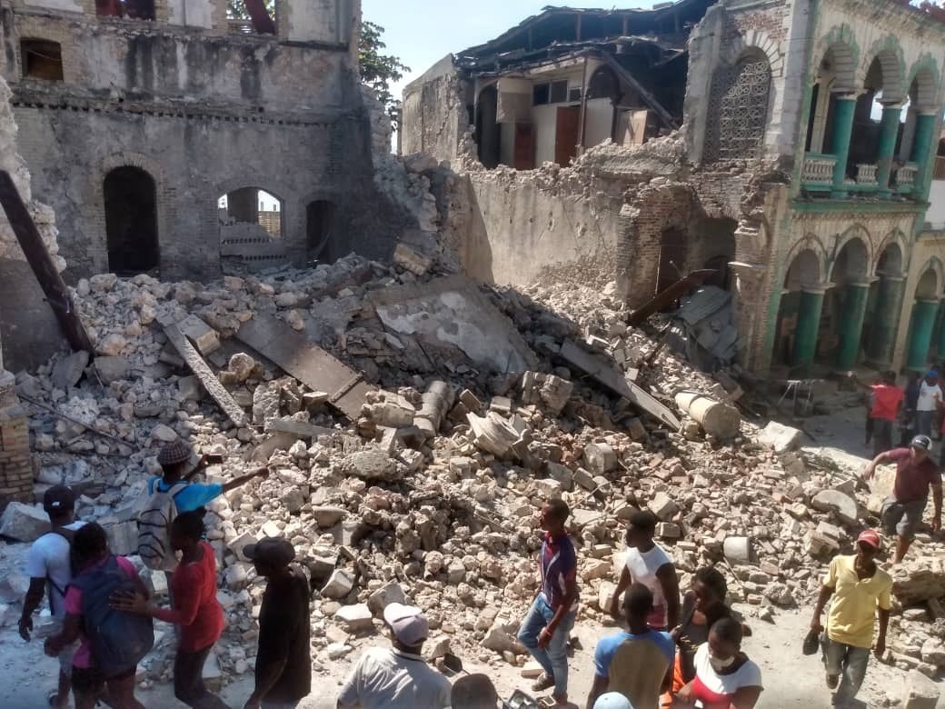 People walk alongside a huge mountain of rubble
