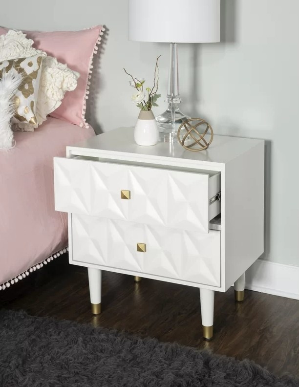 the white nightstand with a lamp on top