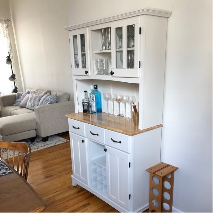 the white dining hutch with glassware in the cabinets