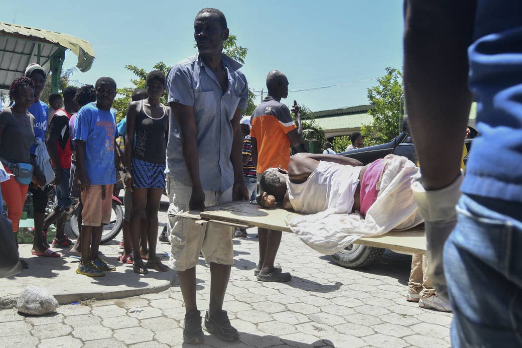 People carry a person lying on their side on a stretcher