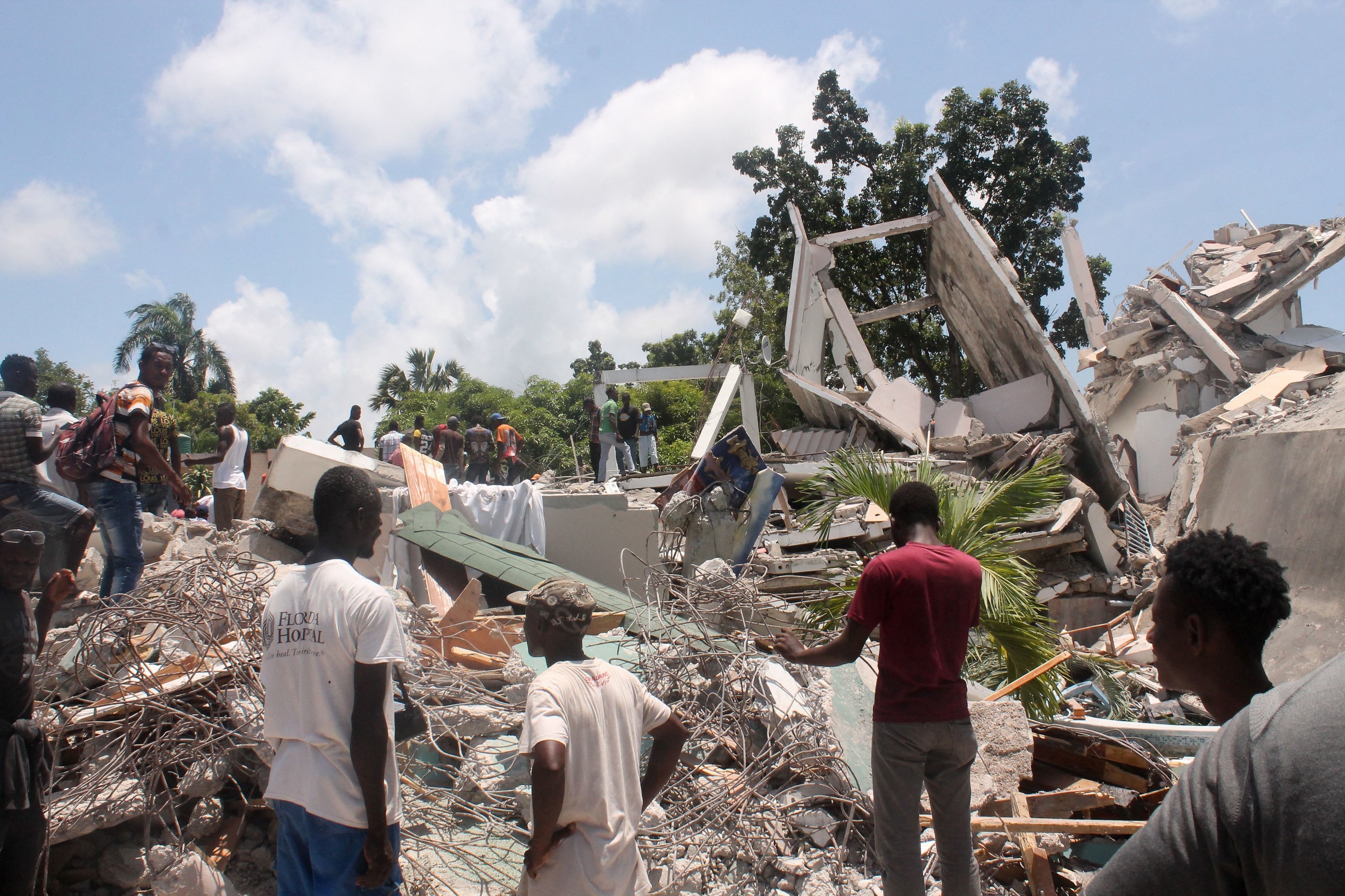 People walk on top of rubble and debris on a sunny day