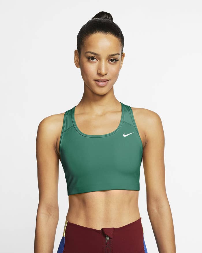 Model wearing green sports bra with white Nike logo