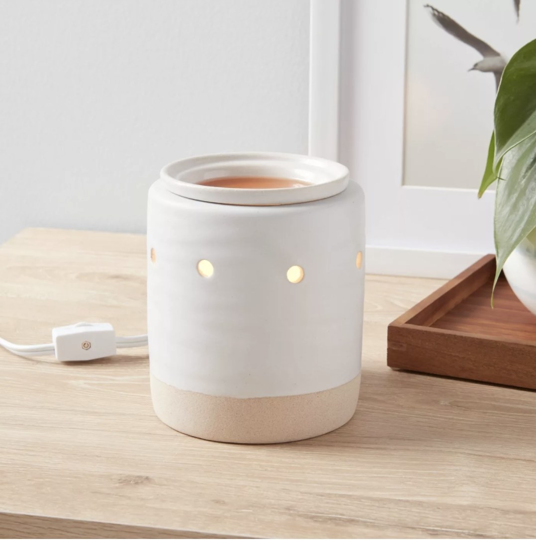 The white and beige warmer is turned on and on top of a natural wooden tabletop