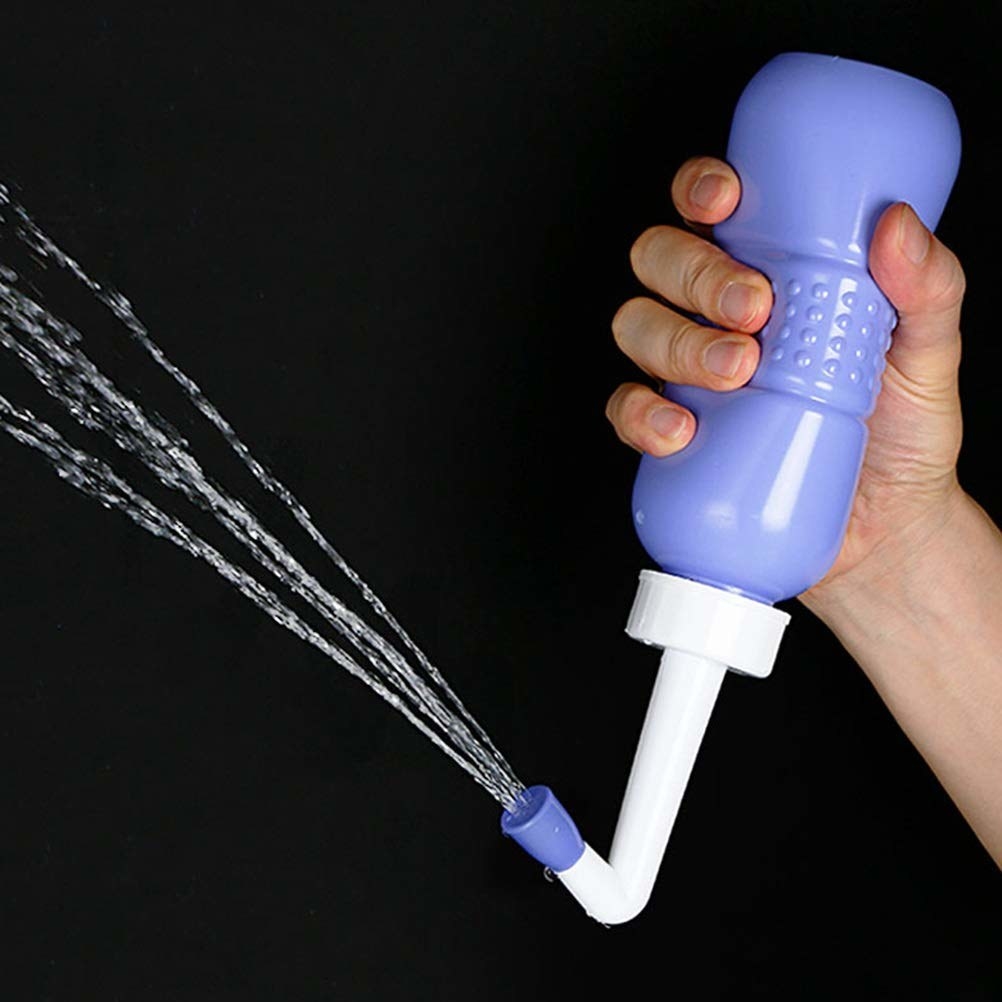A hand squeezing a handheld portable bidet with a jet of water pouring out