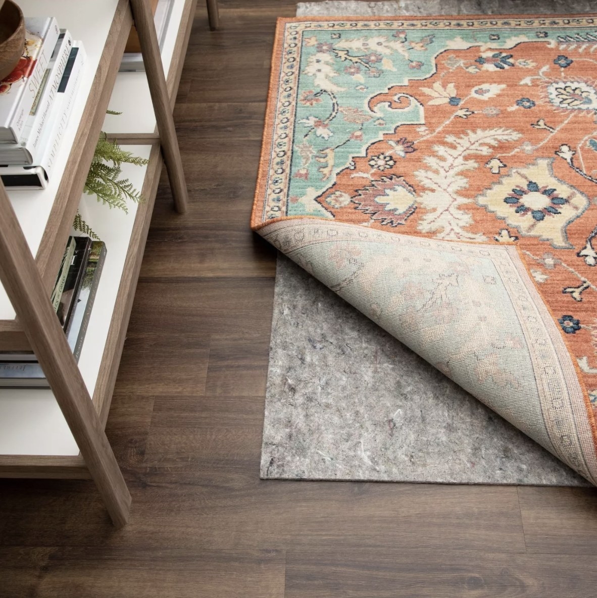The grey rug is underneath a multicolored rug on a dark wooden floor