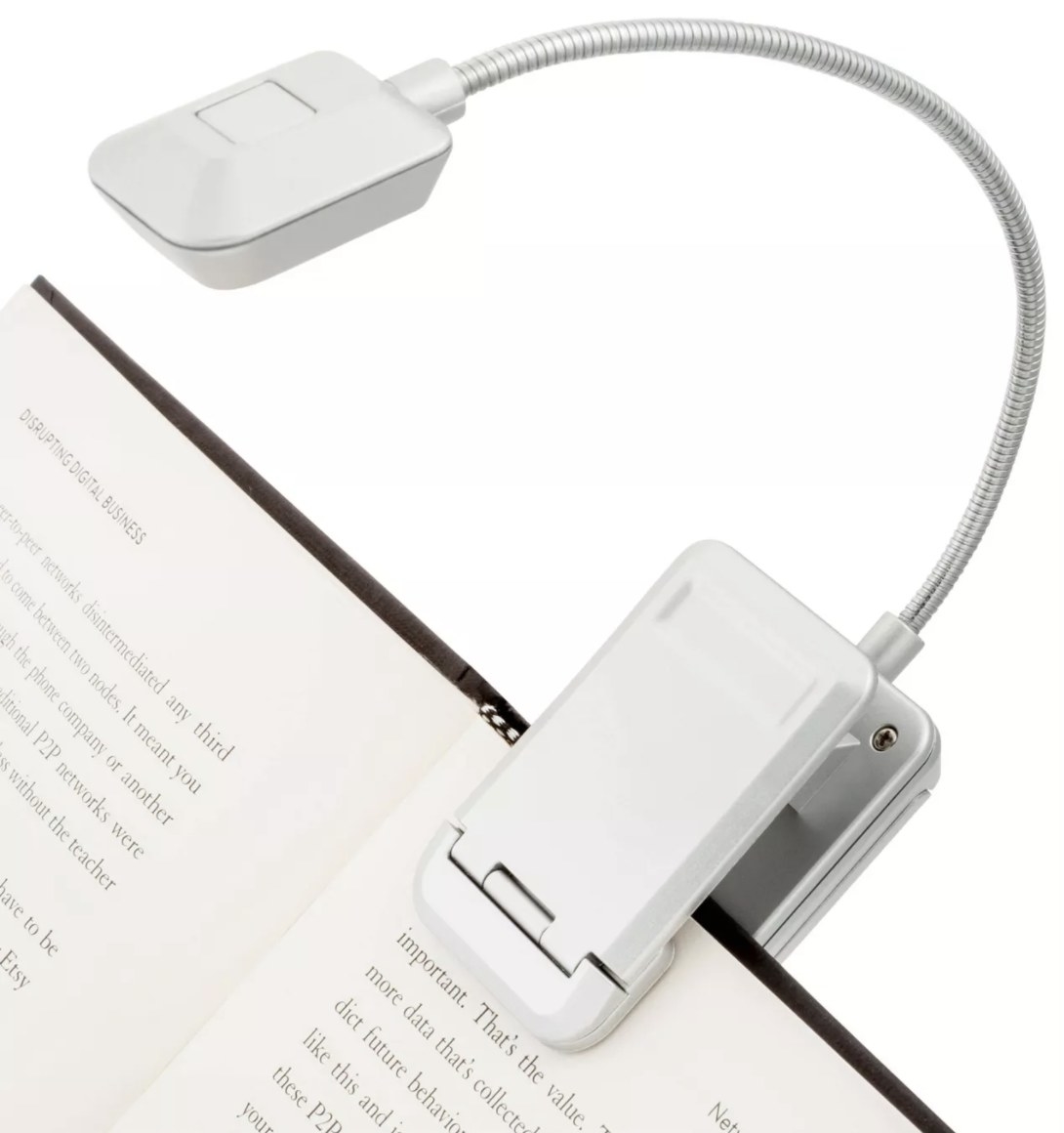 The white light is clipped to the edge of an open book with a black hardcover
