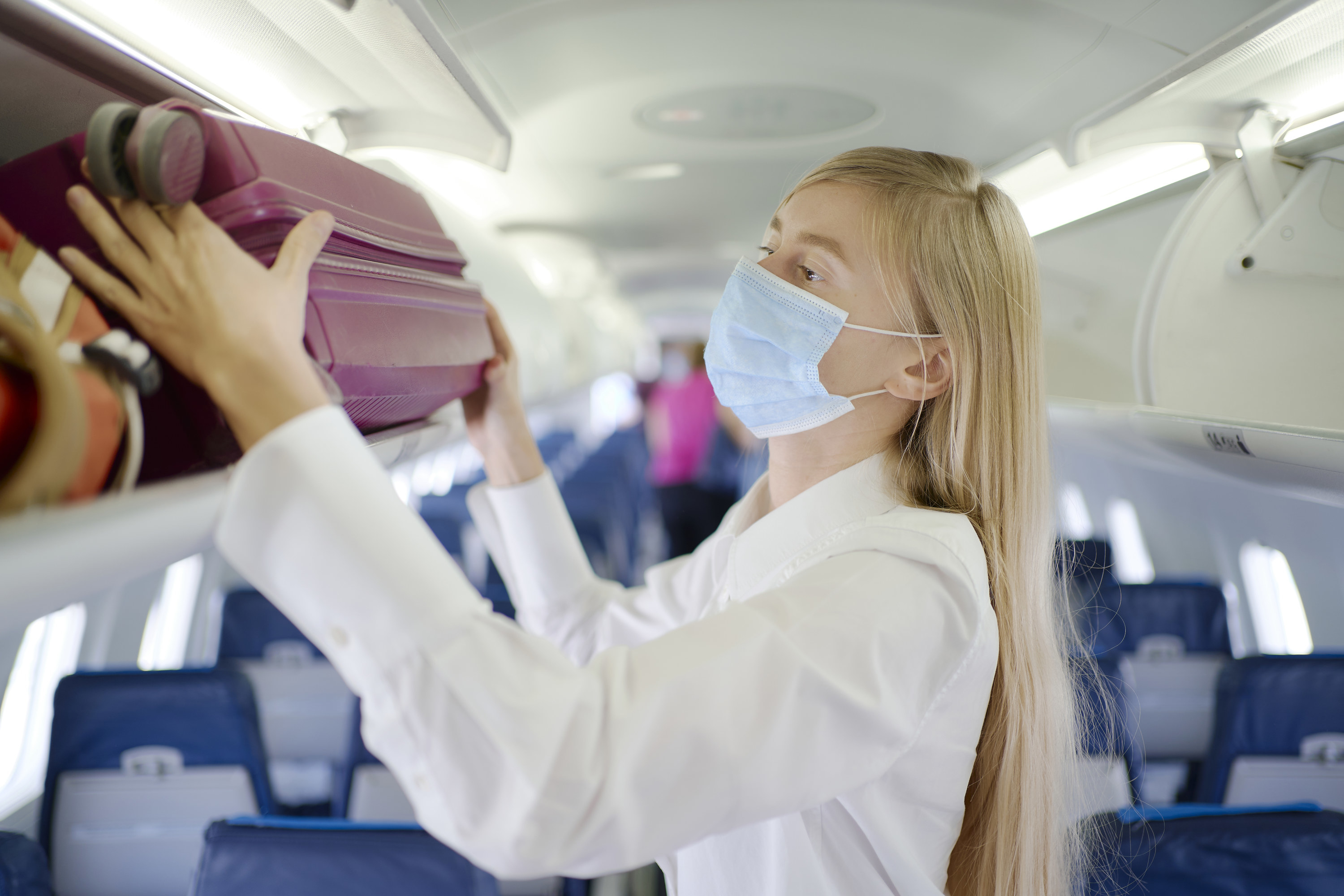Woman puts carry-on bag in the overhead bin