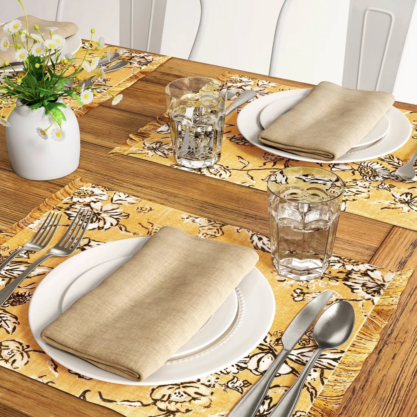The yellow placemat with a black and white floral print underneath a place setting