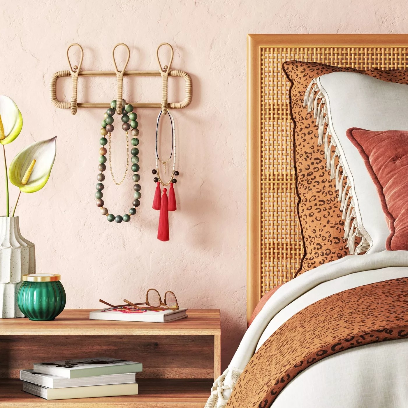 The wall hook next to a bed holding several necklaces