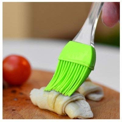 A person using the silicone brush to brush butter over an unbaked pastry