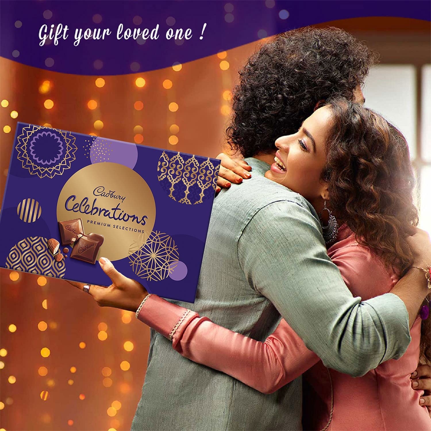 A man and a woman hugging while the woman holds a box of Cadbury celebrations pack in blue and gold colours
