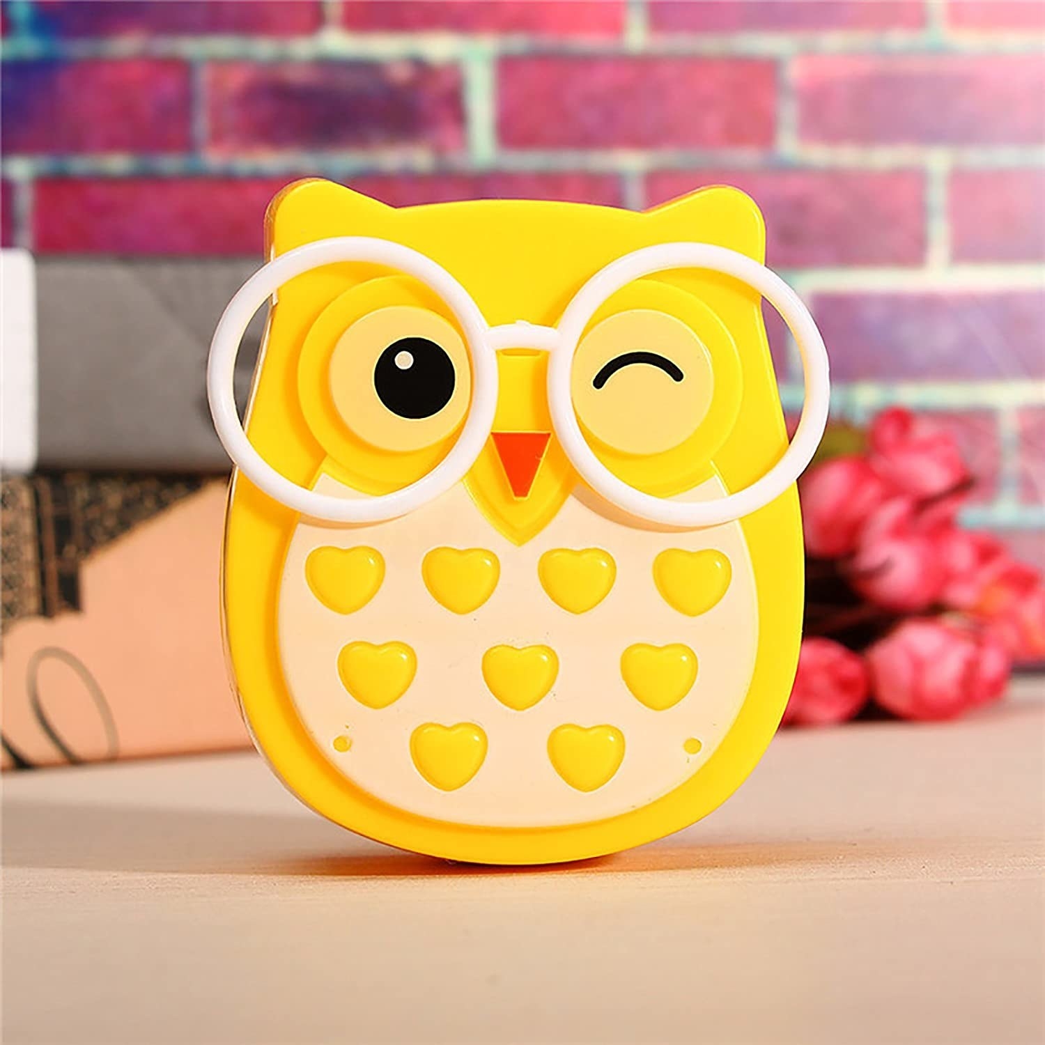 A yellow owl night lamp wearing glasses and winking