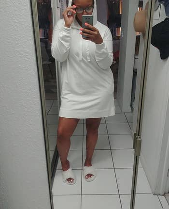 reviewer wearing white above the knee long sleeve dress with hood up