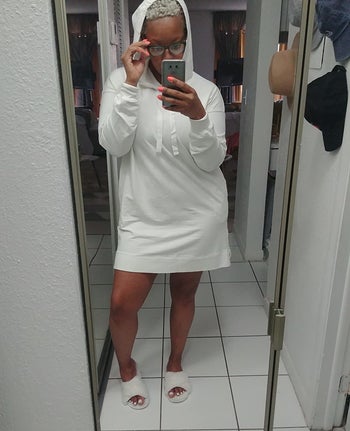reviewer wearing white above the knee long sleeve dress with hood up