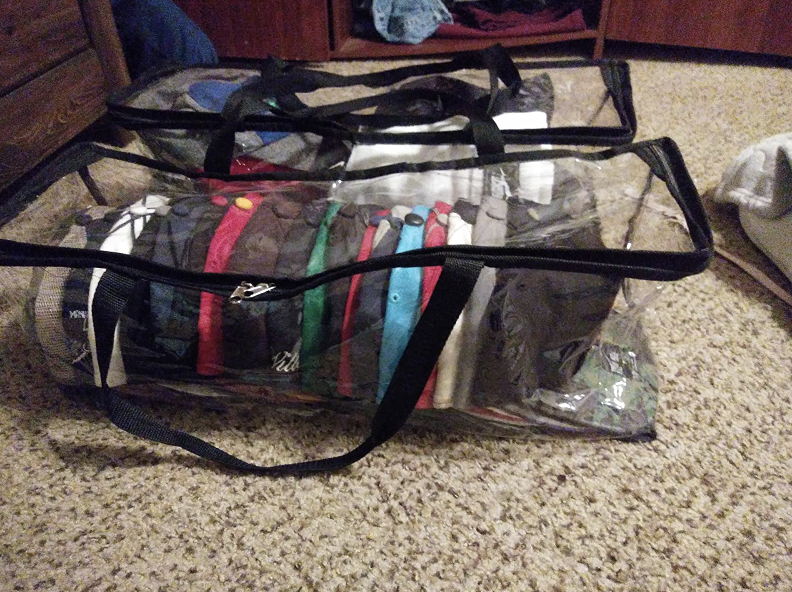 horizontal clear bag with baseball caps stacked inside of it