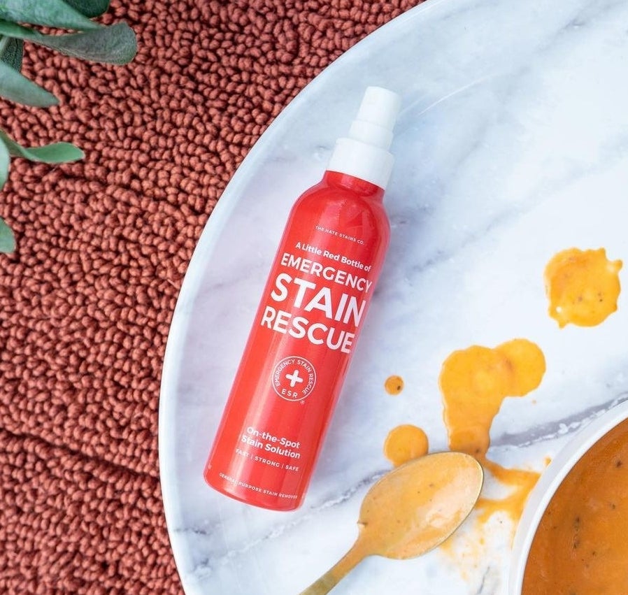 a flatlay of the stain removing spray next to a dirty soup spoon