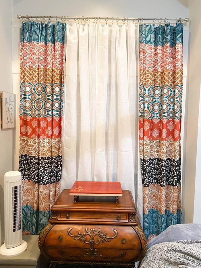 reviewer image of the turquoise and orange curtains hanging behind a wooden armoire