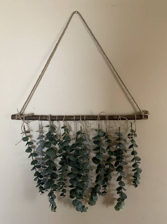 The small wall hanging with a curtain of eucalyptus coming down from a wooden rod