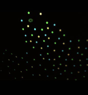 Glow in the dark stars in pink, blue, and green in a dark room