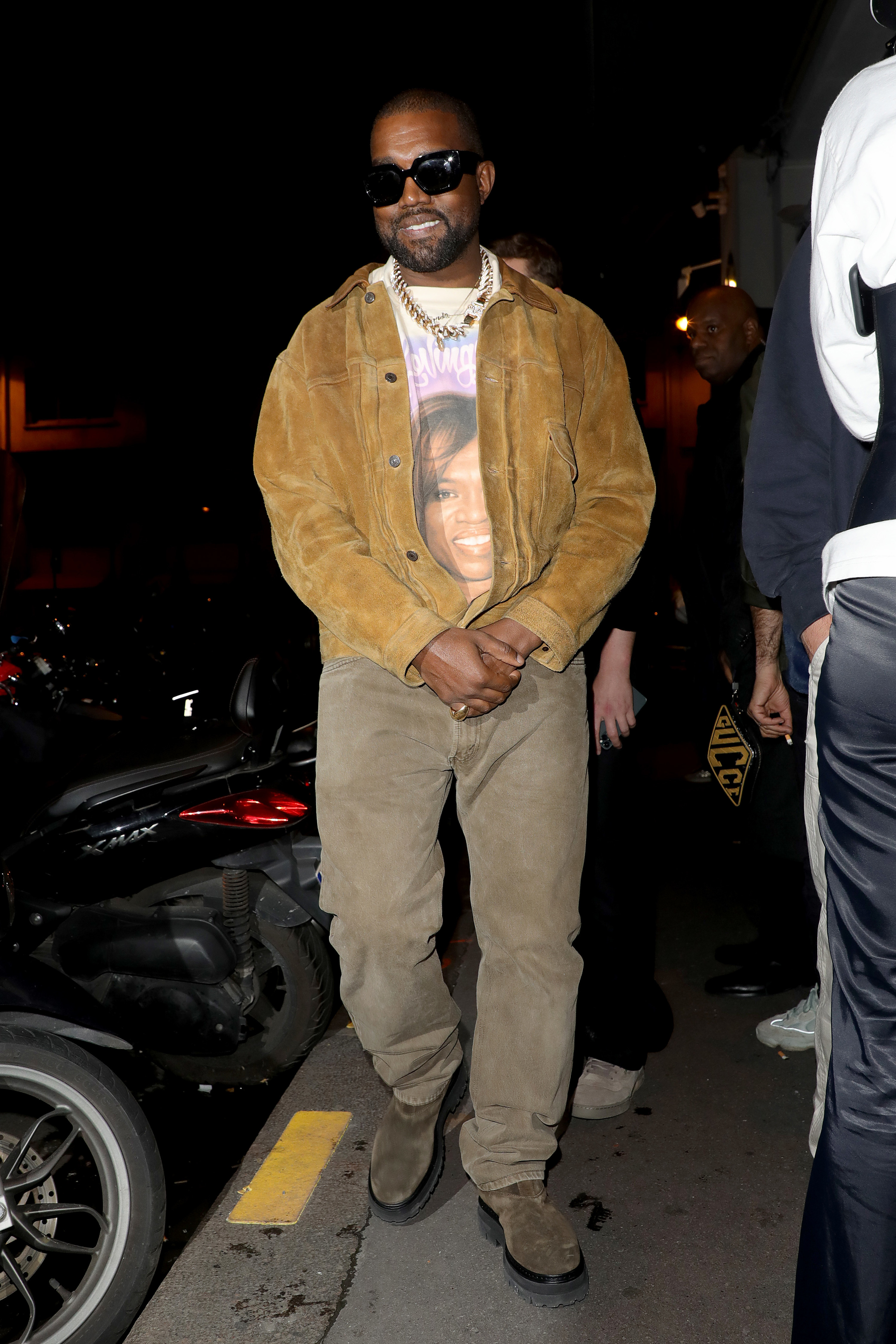 Kanye wears a graphic tee underneath a corduroy jacket and matching corduroy pants.