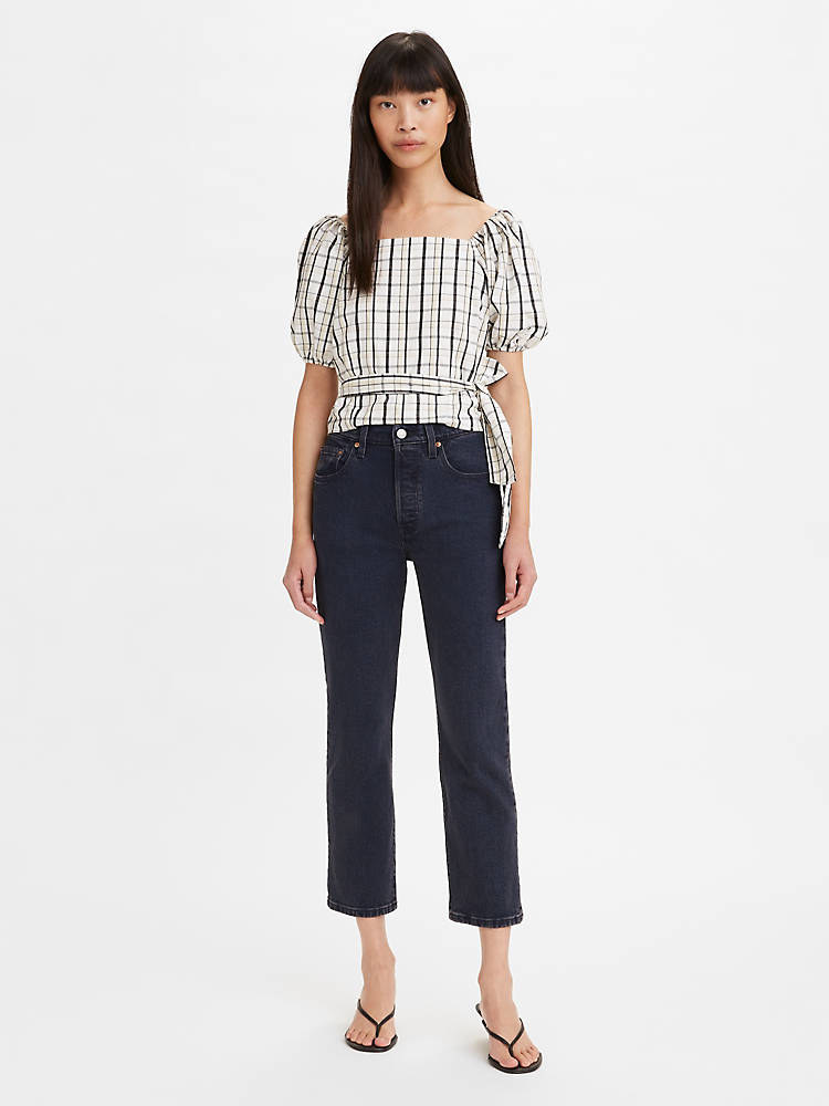 model wearing black and white puff-sleeve blouse with tie waist and dark wash cropped straight-leg jeans
