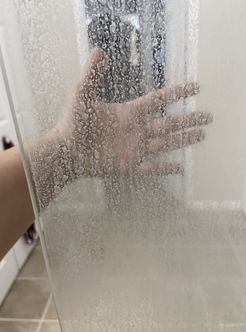 a reviewer's glass shower door looking fogged up from hard water stains