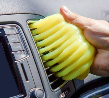 a person using the cleaning gel to clean their car vent