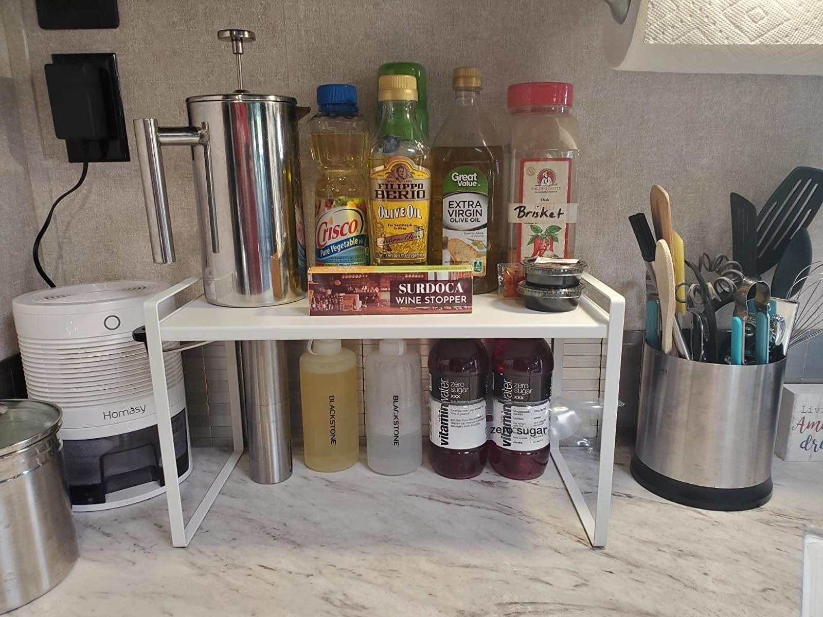 reviewer image of the white countertop organizer on a marble counter organizing oils