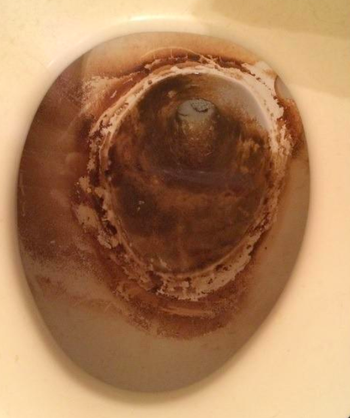 A built-up brown substance inside of a toilet bowl