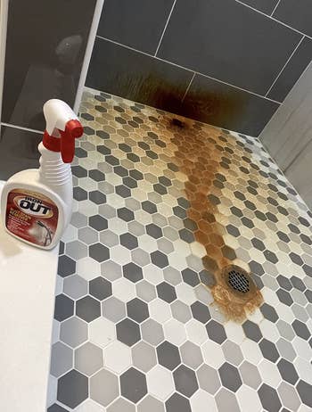 A shower with orange rust on the floor