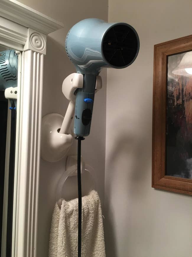 reviewer's adjustable stand mounted to the wall holding up a blow dryer
