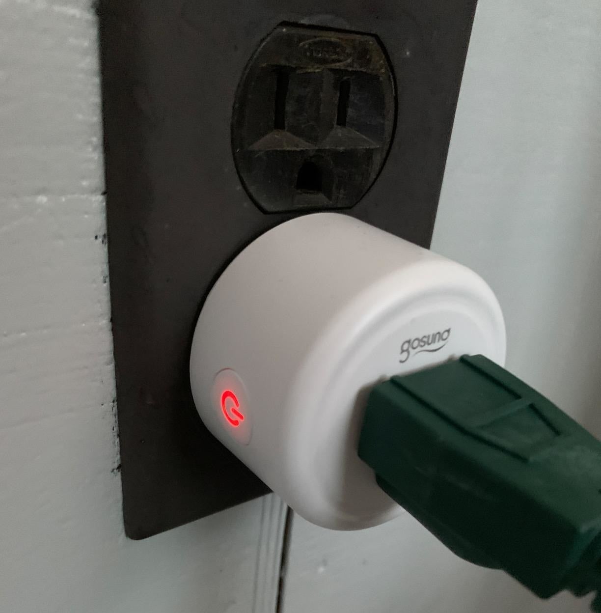 a reviewer photo of a smart outlet plugged into a wall socket