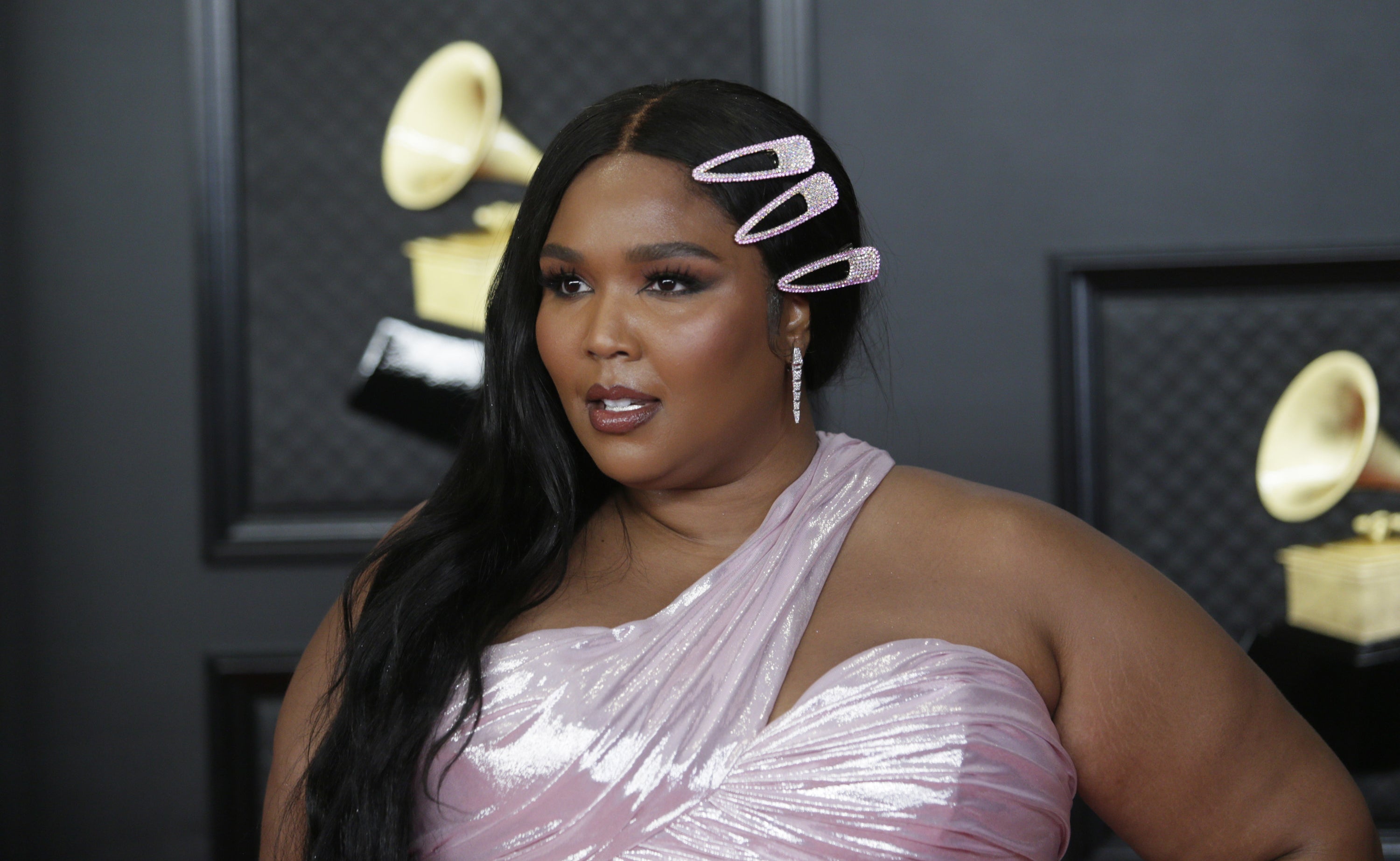 Closeup of Lizzo in a pink gown looking at someone off-camera